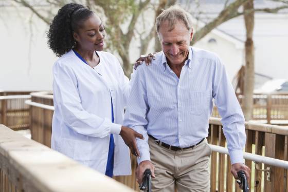 Nurse helping senior man with walker